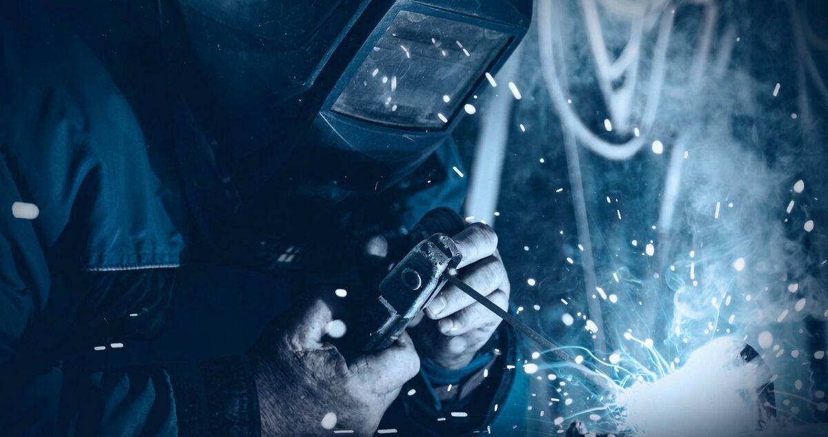 Welder fabricating steel building components with sparks flying